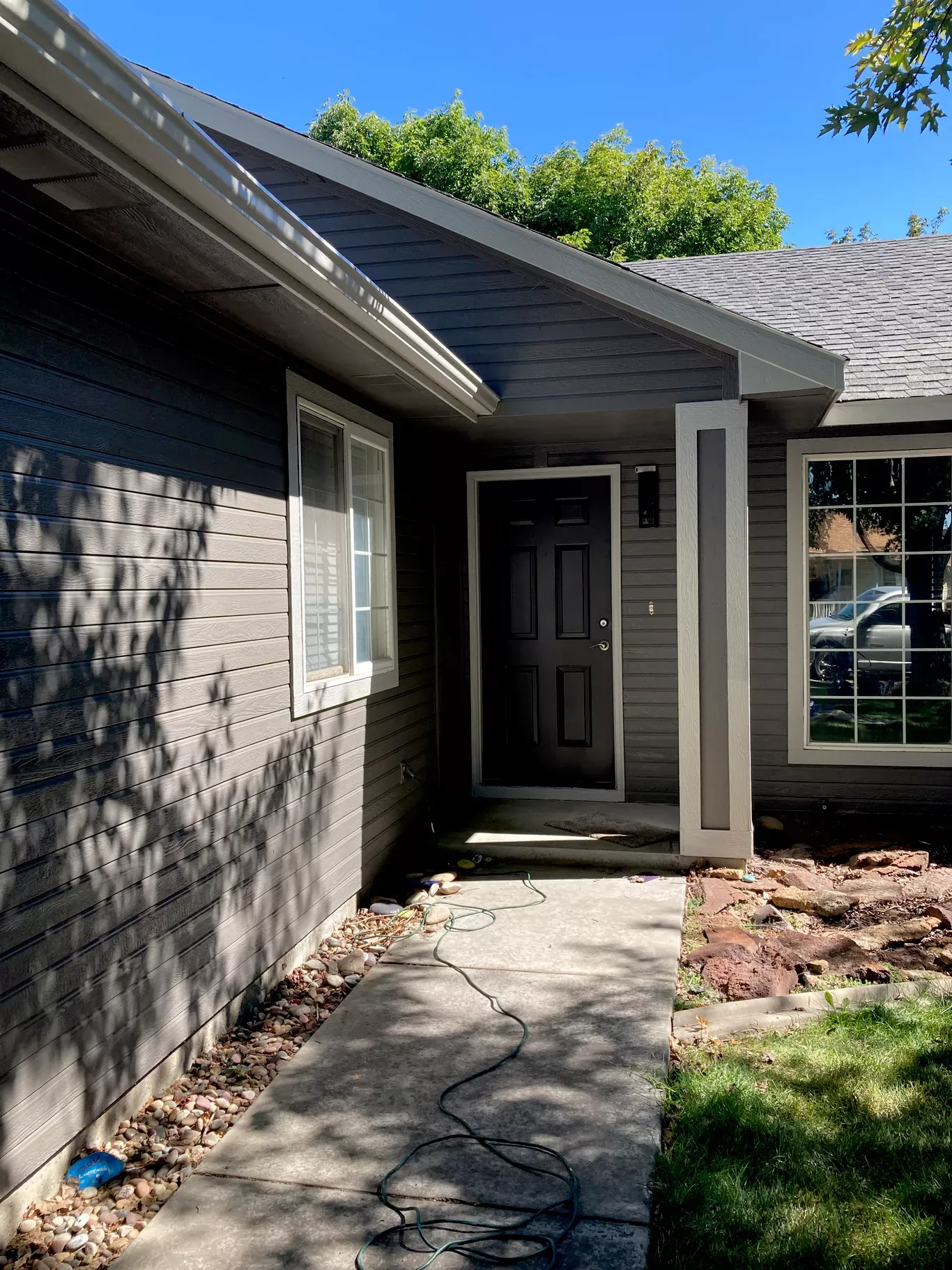 After: gray siding, white trim and dark entry door after exterior painting in Star, Idaho