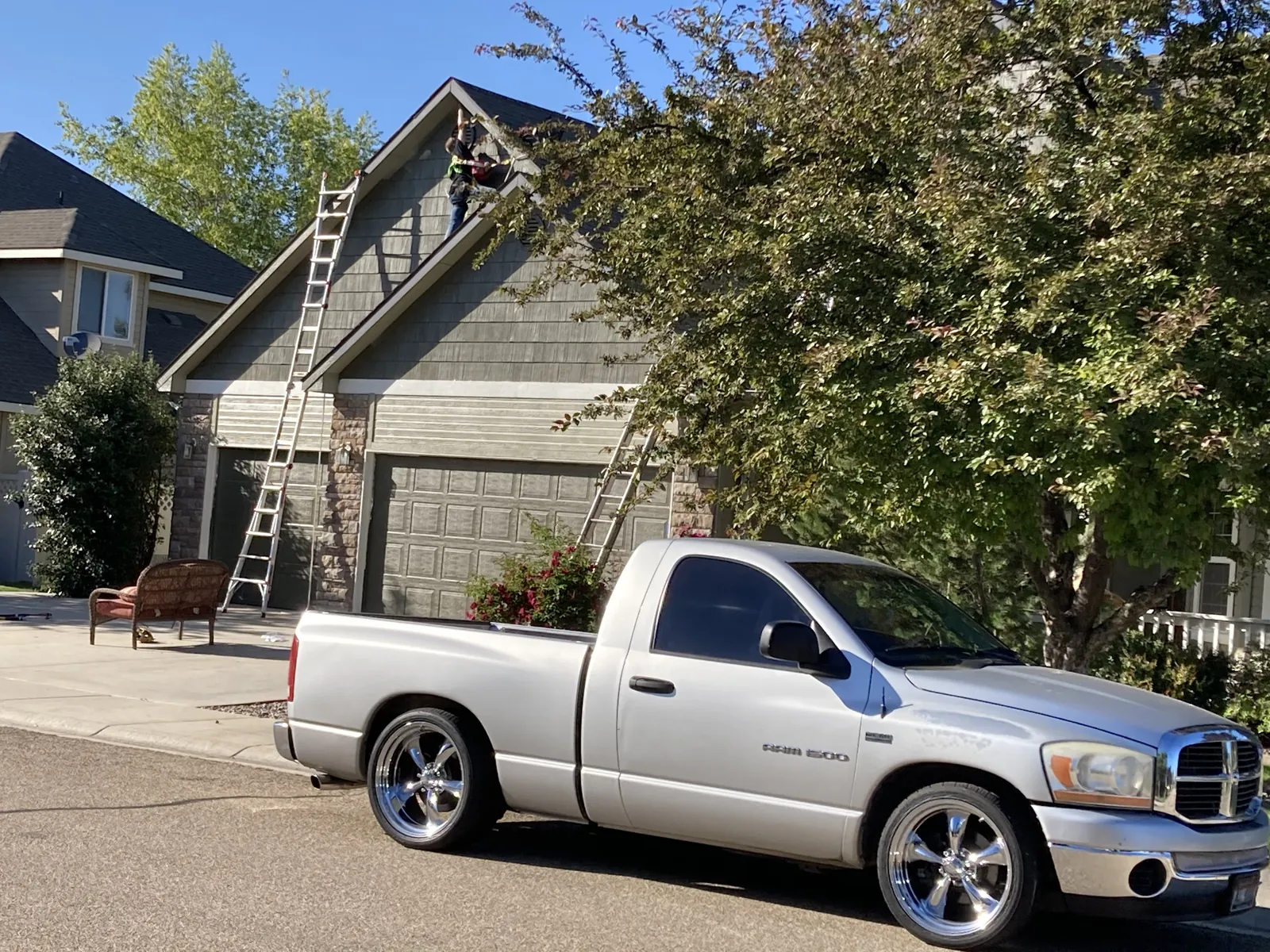 Two-story home exterior being painted with ladders set up, Glenn Painting Co truck in driveway, Treasure Valley
