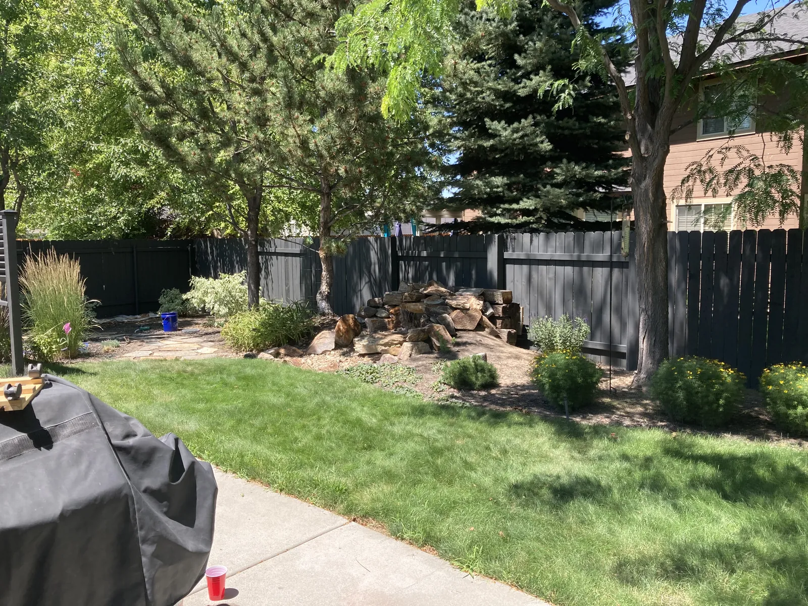 Long run of dark-stained backyard fence with trees and lawn in Star, Idaho
