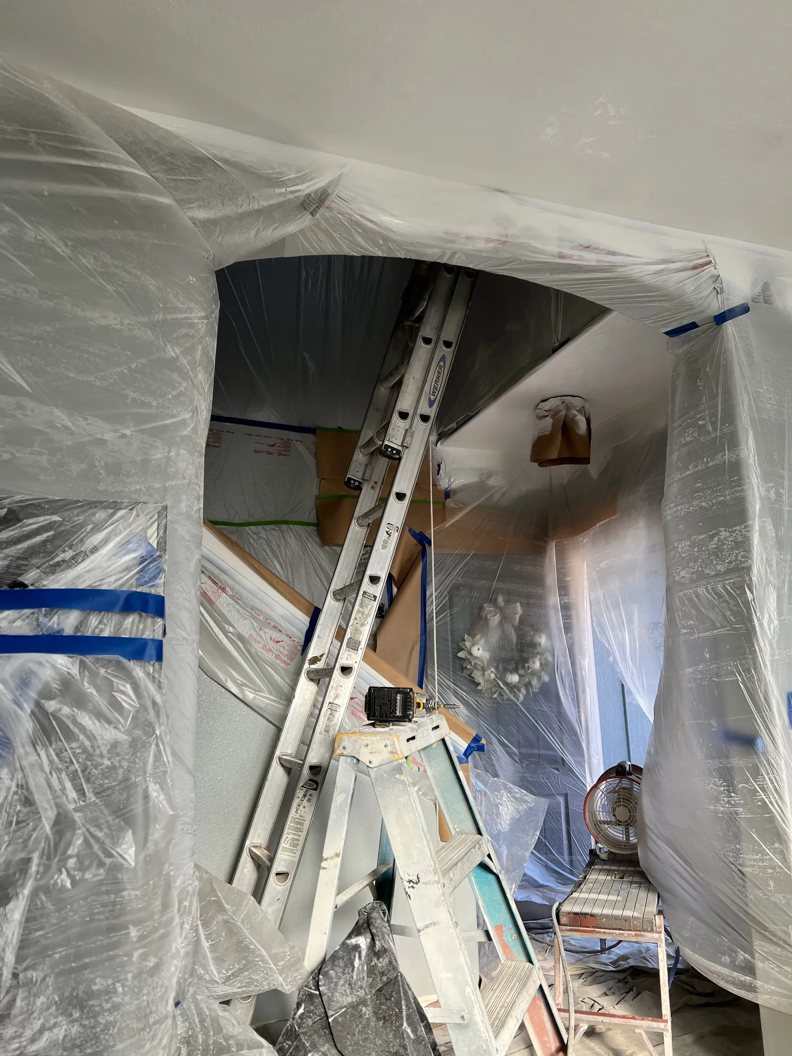 Archway and room fully masked in plastic with ladders ready for interior painting