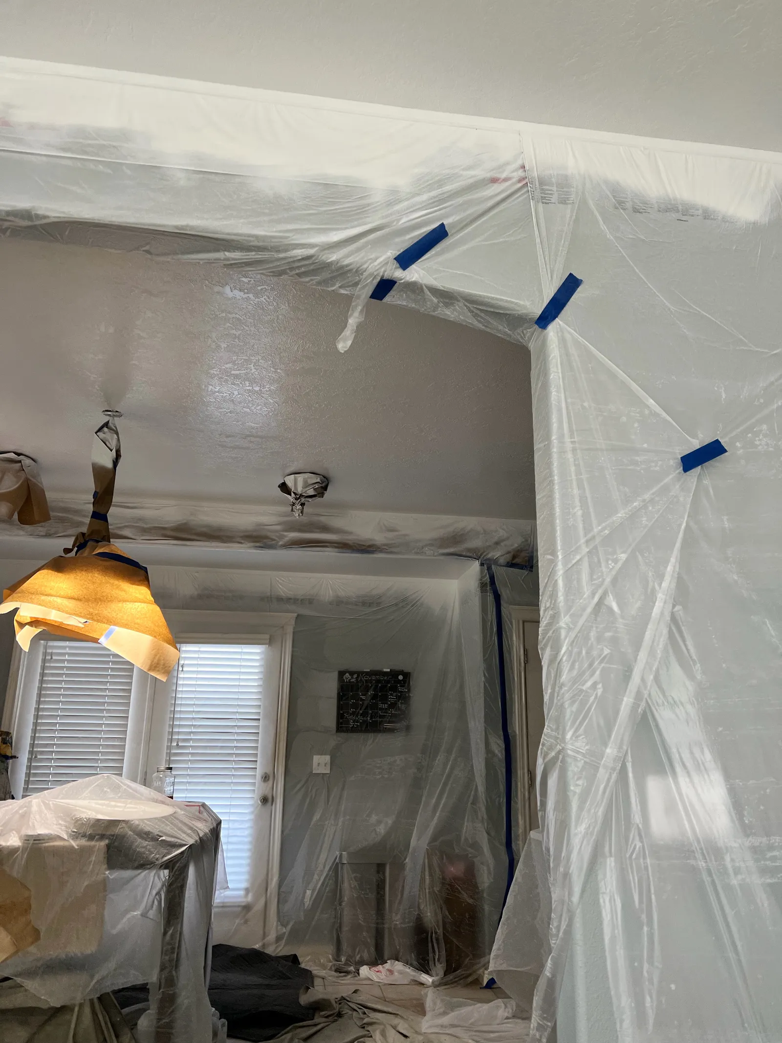 Living room walls and light fixture masked before spraying the ceiling