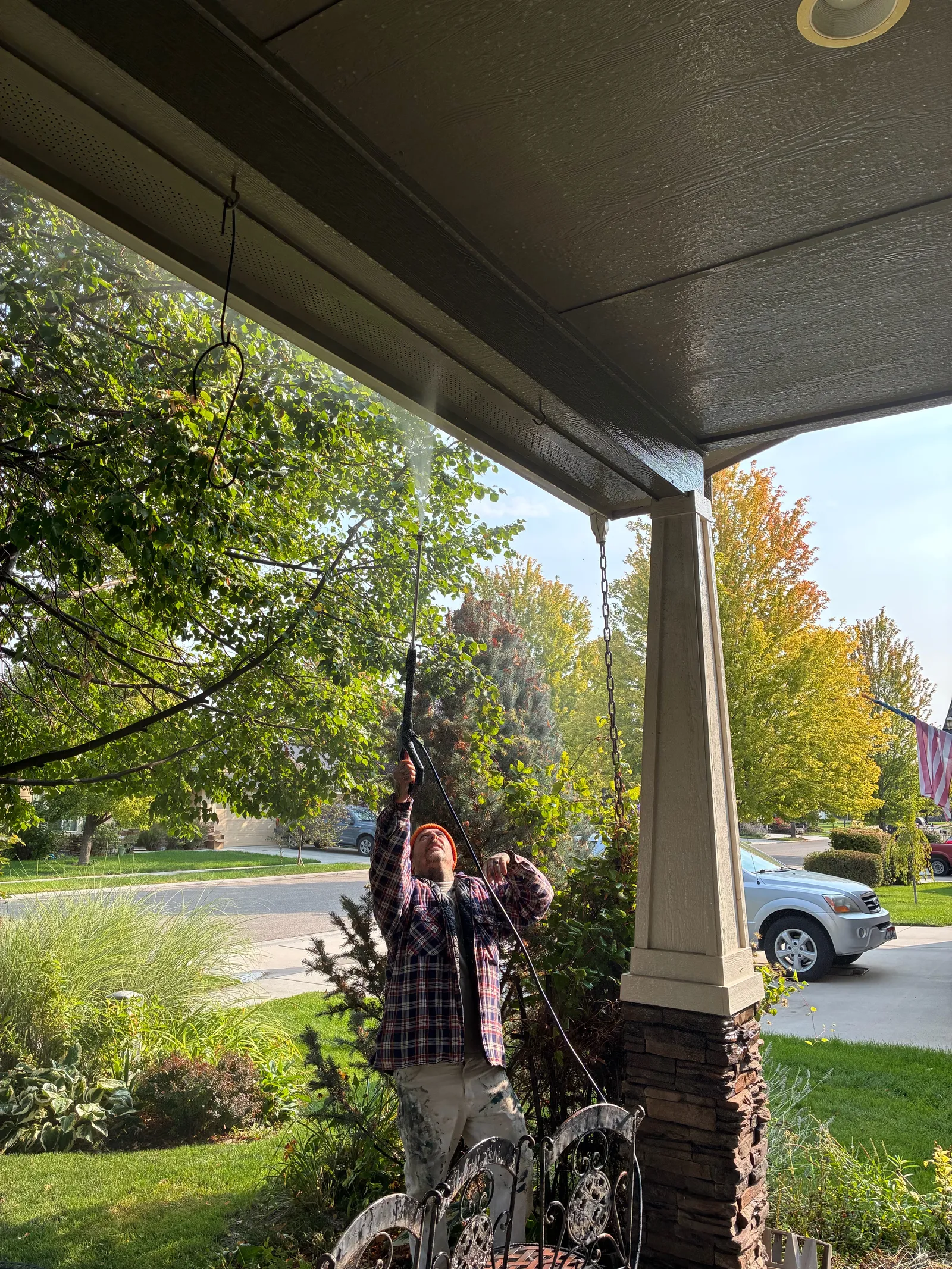 Power washing a porch soffit and eaves to remove dirt and cobwebs