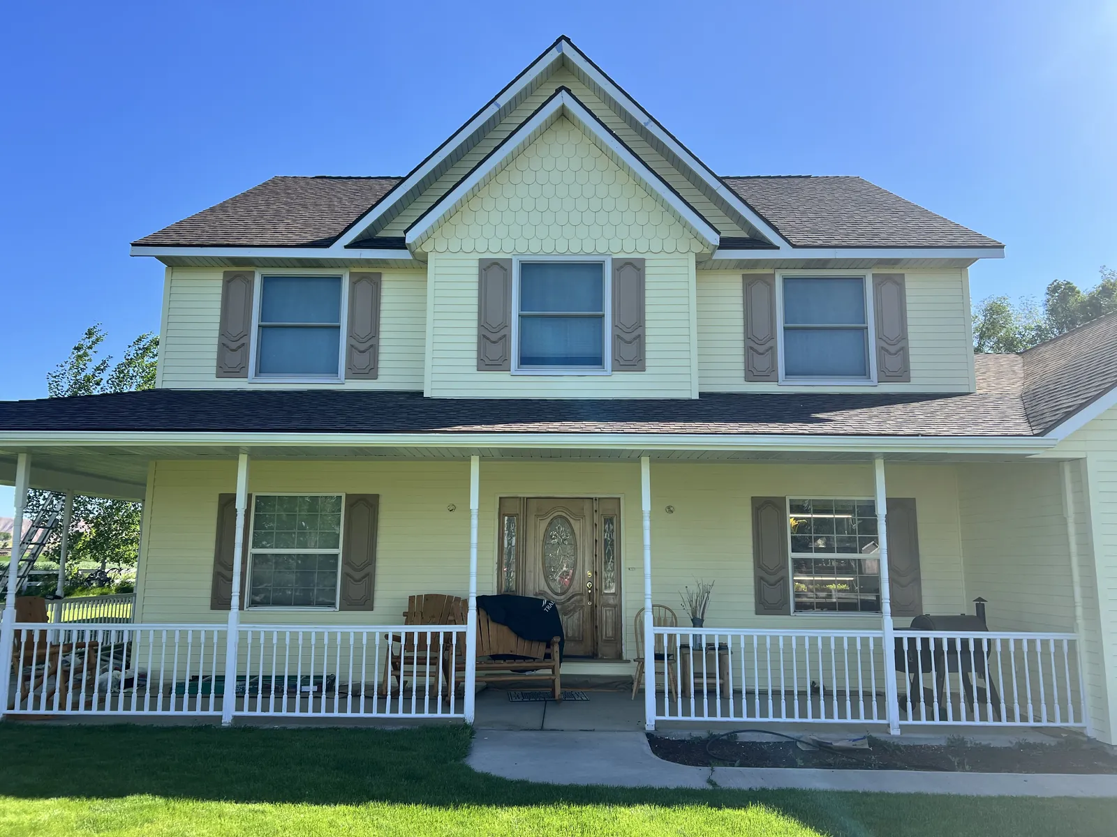 Two-story yellow home with white porch railings after exterior painting in Star, Idaho